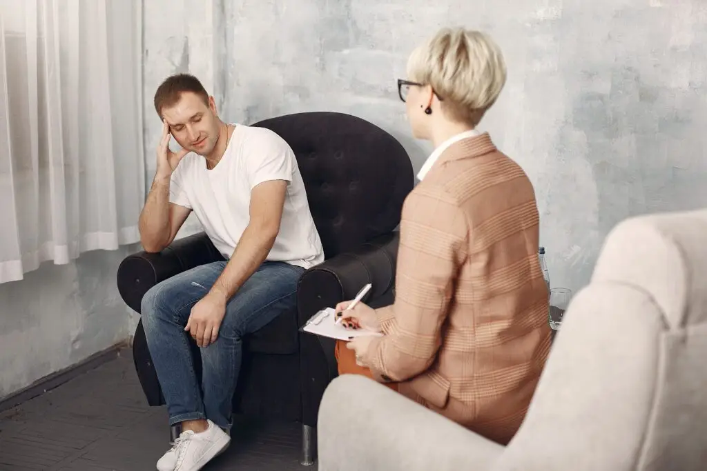 A man sitting on a chair talking to a woman.